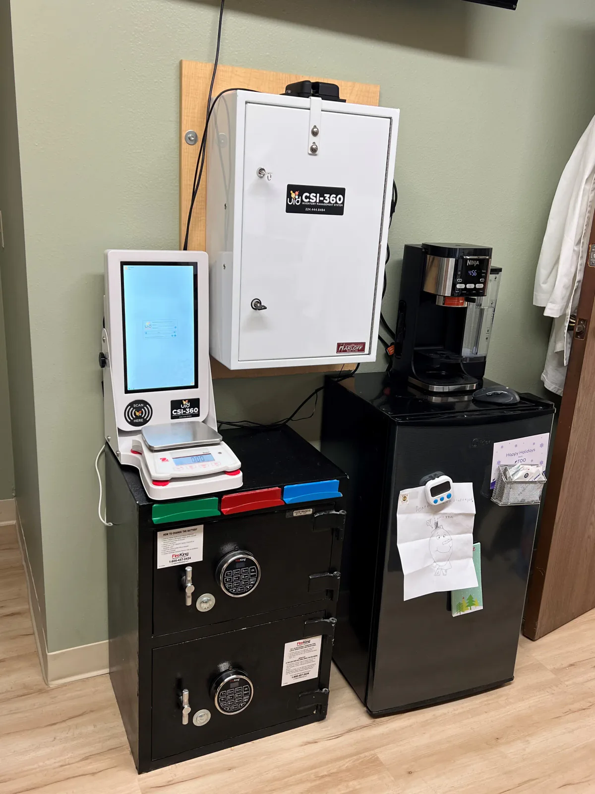CSI-360 touchscreen and digital scale on a black floor safe beneath a wall-mounted white controlled-substance cabinet