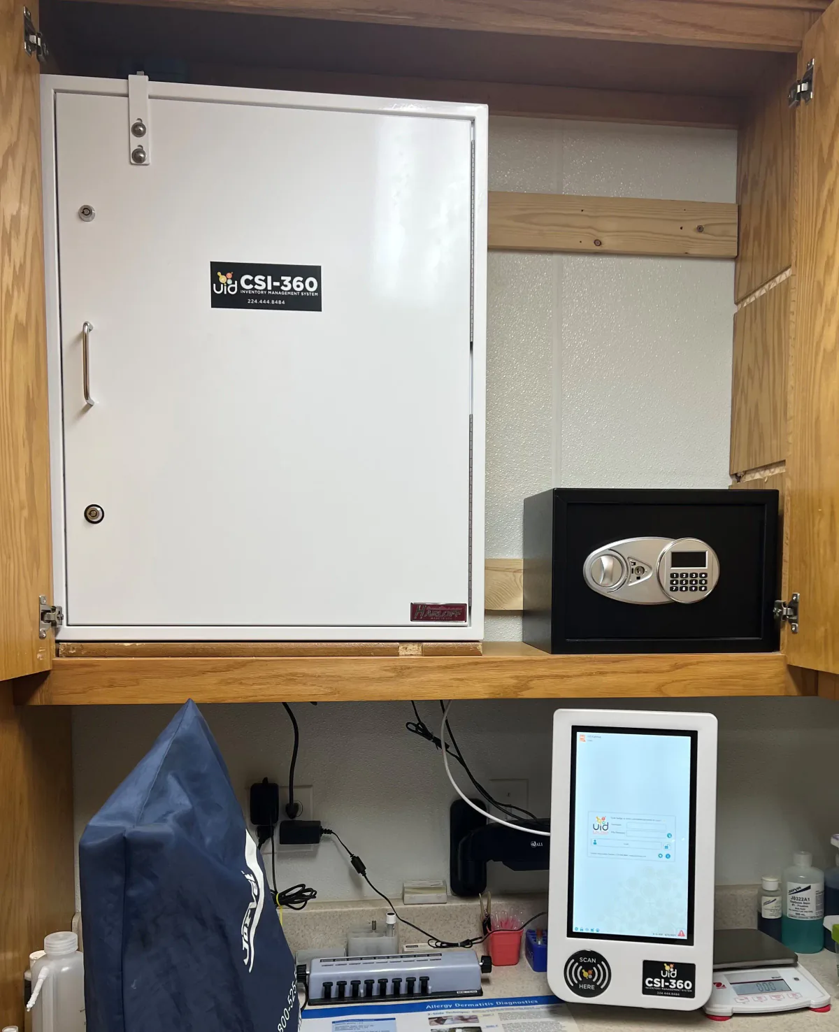CSI-360 touchscreen and digital scale beneath white and black controlled-substance cabinets built into existing clinic cabinetry